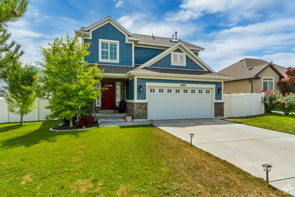 Craftsman-style house with concrete driveway, stone siding, and an attached garage