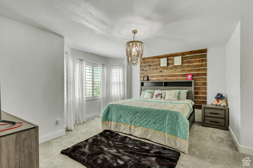 Carpeted bedroom with a chandelier and baseboards