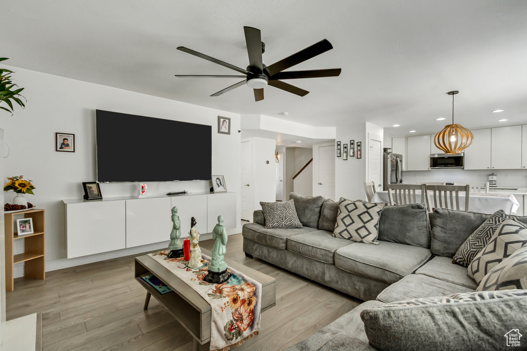Living room with a ceiling fan, light wood finished floors, recessed lighting, and stairs