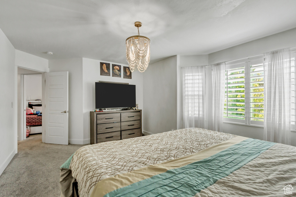 Carpeted bedroom with a chandelier and baseboards
