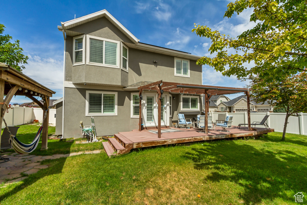 Back of house featuring stucco siding, a pergola, a fenced backyard, and a deck