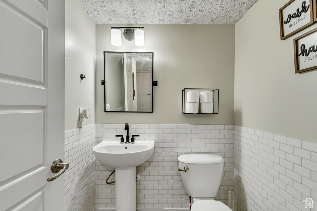 Half bath featuring tile walls and wainscoting