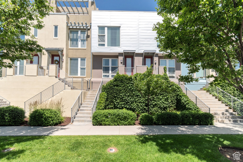 View of front of home featuring stairs, stucco siding, and a front yard