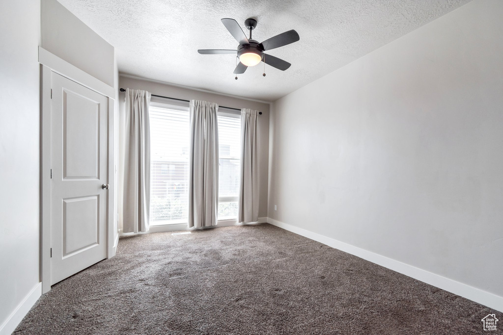 Spare room with a textured ceiling, carpet flooring, and a ceiling fan