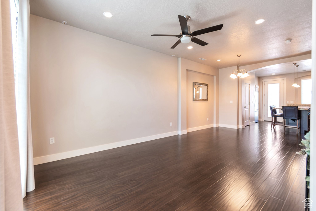 Unfurnished living room with dark wood finished floors, a chandelier, ceiling fan, and recessed lighting