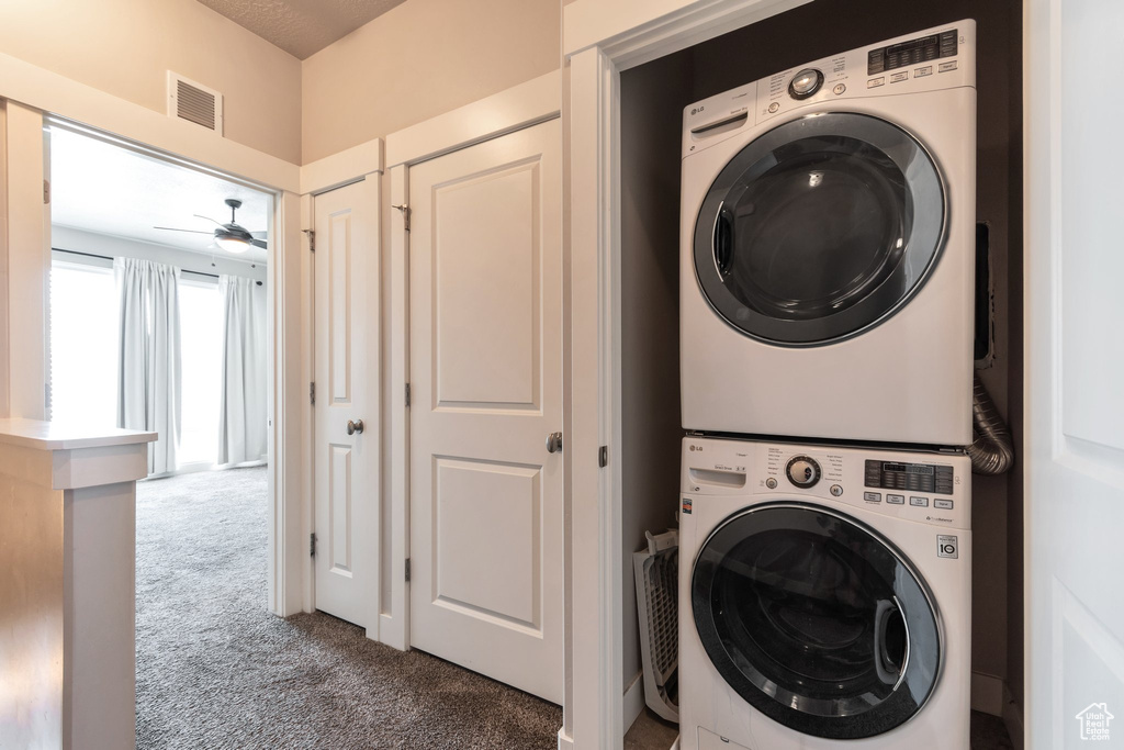 Laundry room featuring estacked washer and dryer, carpet floors, and ceiling fan