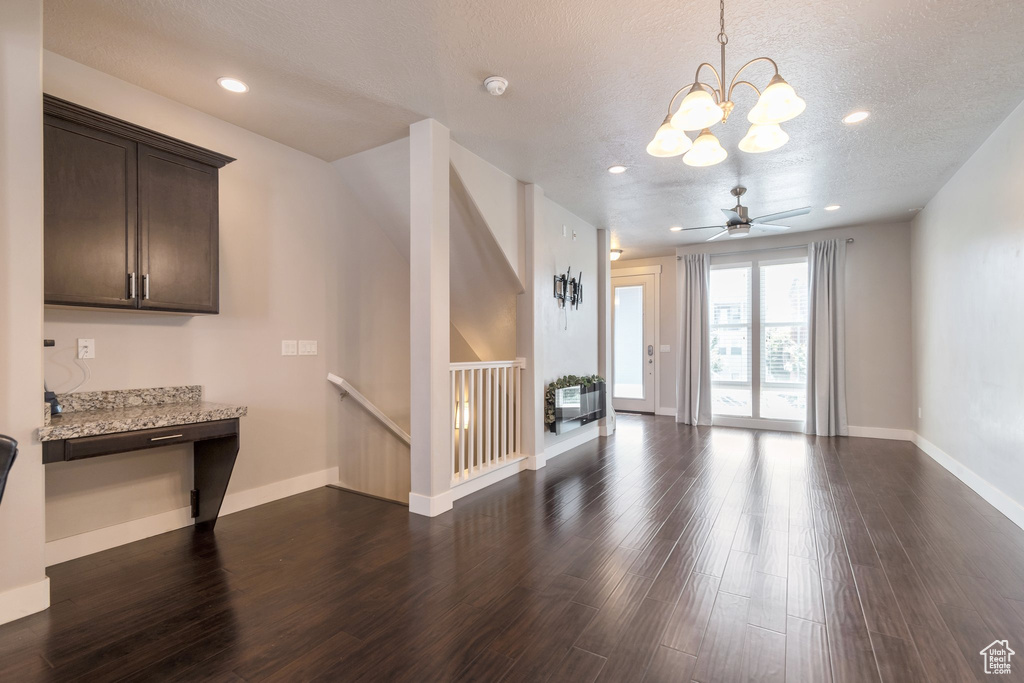Unfurnished living room featuring a chandelier, dark wood finished floors, a textured ceiling, and recessed lighting