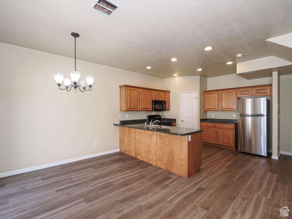 Kitchen featuring freestanding refrigerator, black microwave, a peninsula, recessed lighting, and dark wood-style flooring