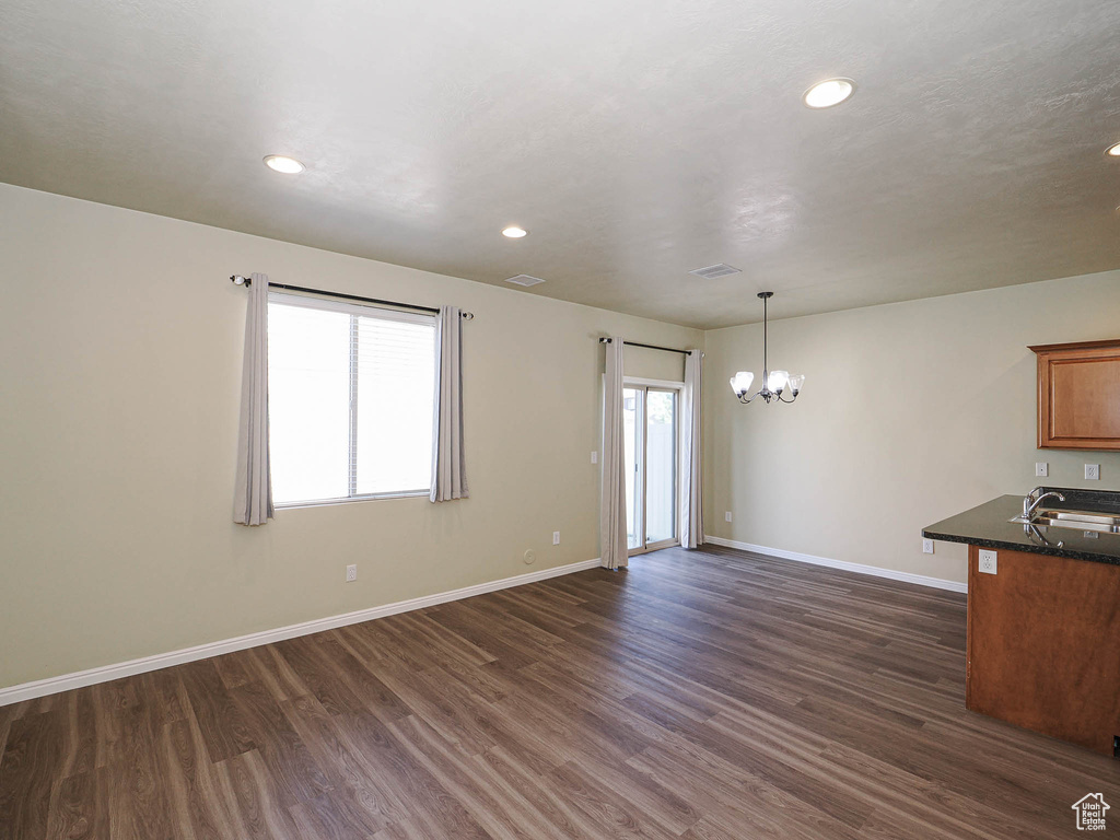 Empty room featuring a chandelier, dark wood-style flooring, and recessed lighting