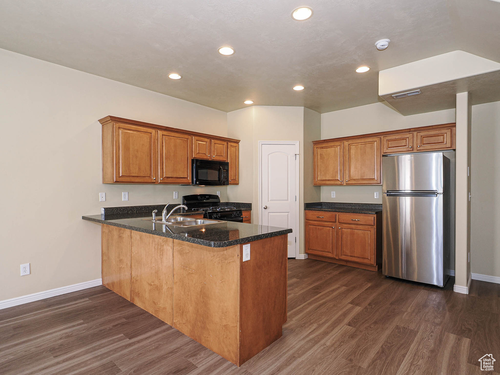Kitchen with black appliances, dark wood-style floors, a peninsula, recessed lighting, and brown cabinetry