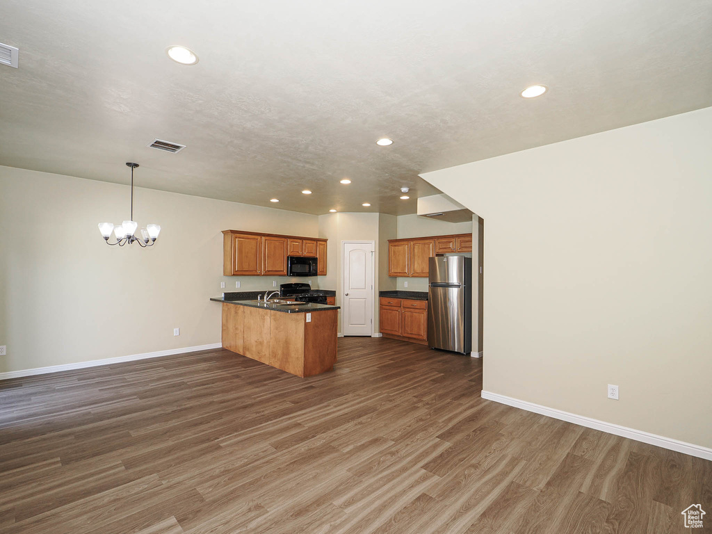 Kitchen featuring black microwave, freestanding refrigerator, recessed lighting, a peninsula, and a chandelier