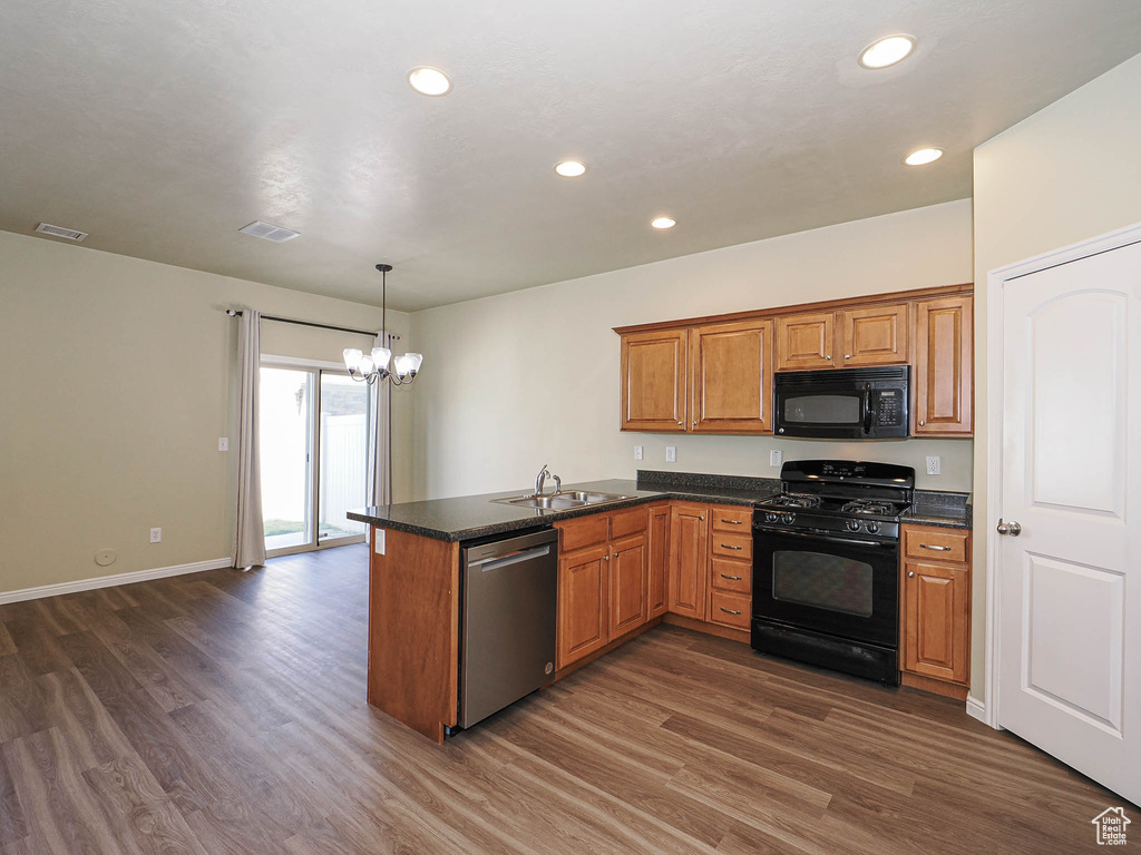 Kitchen featuring black appliances, a chandelier, a peninsula, dark wood-style flooring, and brown cabinets