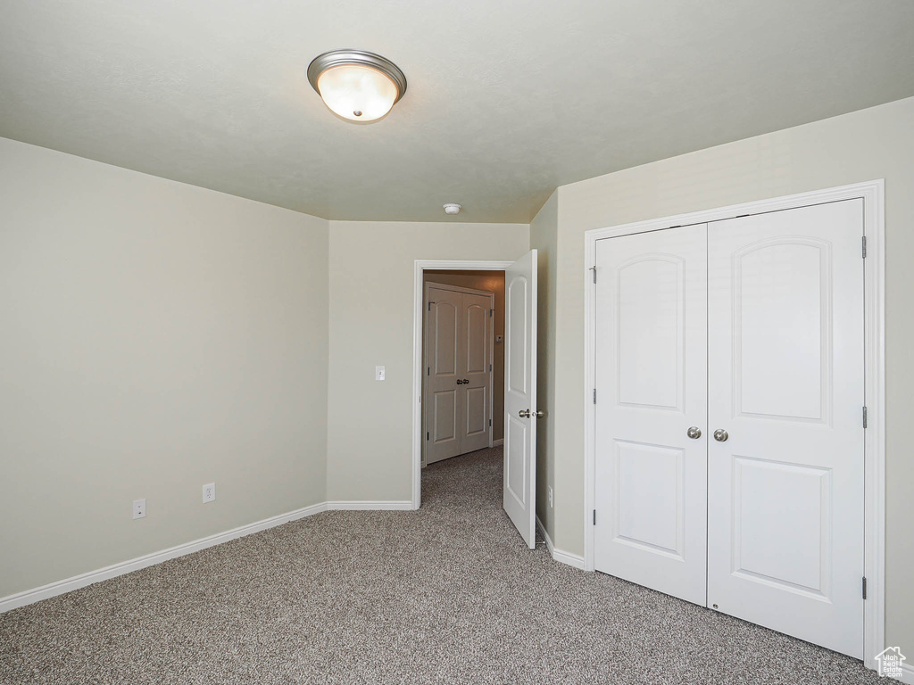 Unfurnished bedroom with light carpet and a closet
