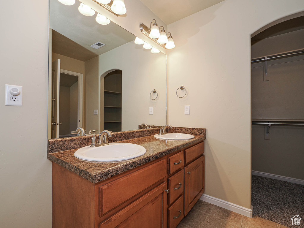 Full bathroom with double vanity, a spacious closet, and tile patterned floors