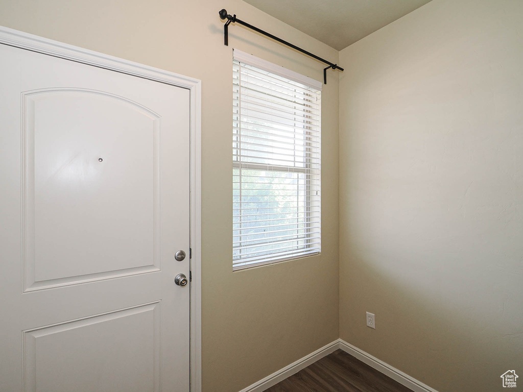 Doorway featuring baseboards and dark wood-style flooring