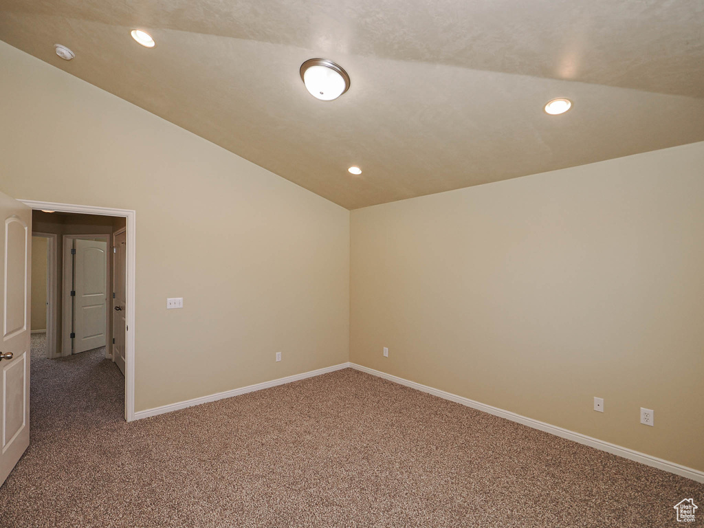 Empty room featuring lofted ceiling, carpet, recessed lighting, and a smoke detector