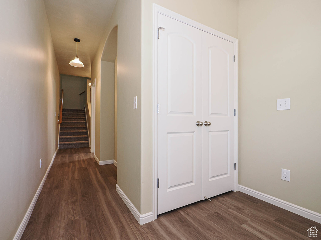 Hall featuring dark wood-style flooring, arched walkways, and stairway