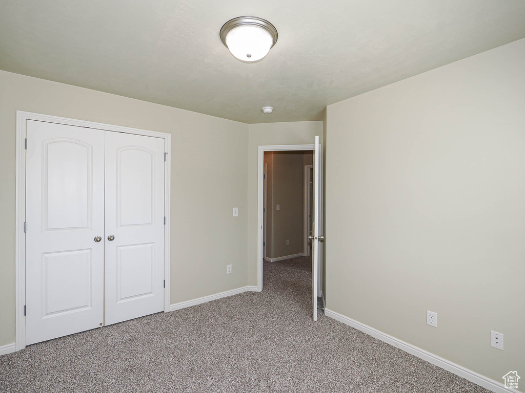 Unfurnished bedroom with light carpet and a closet