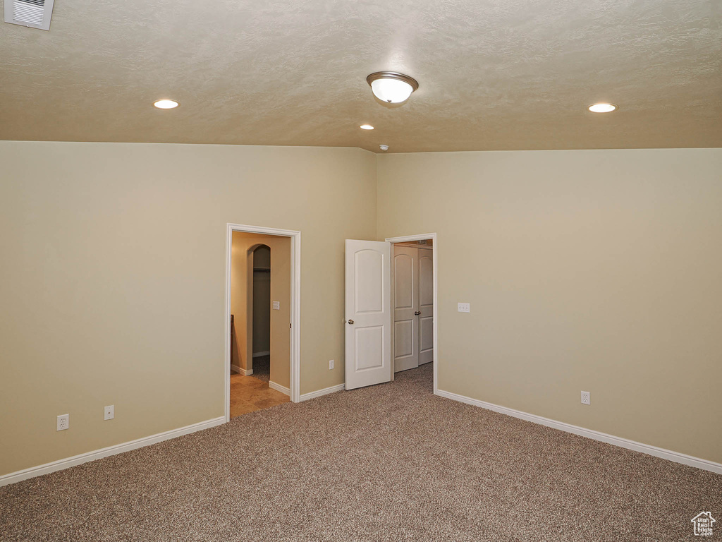 Spare room with recessed lighting, carpet, vaulted ceiling, arched walkways, and a textured ceiling