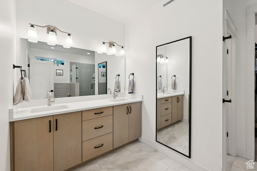 Full bath featuring marble finish flooring, double vanity, and a stall shower