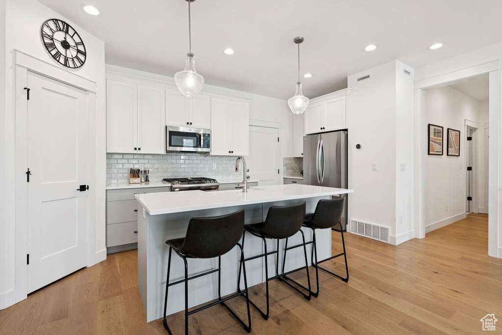 Kitchen with appliances with stainless steel finishes, backsplash, a breakfast bar area, light countertops, and recessed lighting