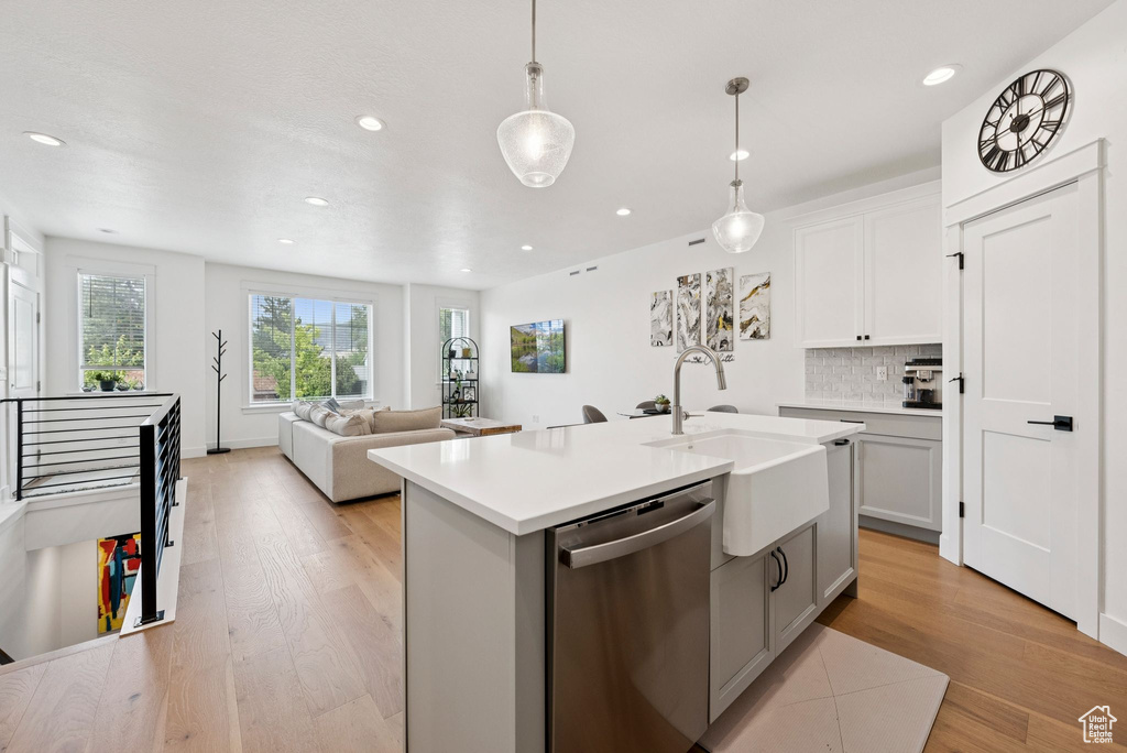Kitchen with stainless steel dishwasher, decorative backsplash, light wood-type flooring, light countertops, and recessed lighting