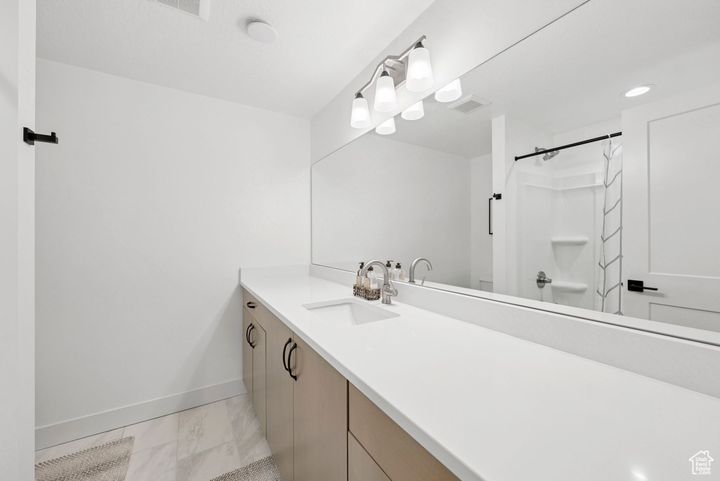 Full bath with vanity, marble look tiles, a shower, and recessed lighting