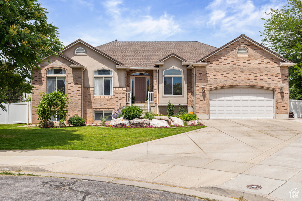 View of front facade featuring driveway, a garage, stucco siding, and brick siding