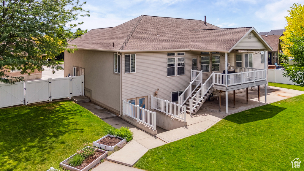Back of house featuring a gate, a fenced backyard, a wooden deck, roof with shingles, and a garden