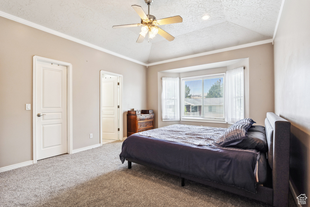 Bedroom with vaulted ceiling, a textured ceiling, crown molding, carpet floors, and a ceiling fan