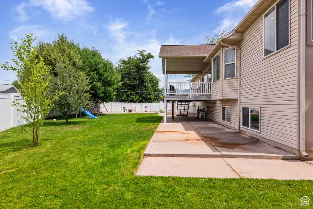 Fenced backyard featuring a playground, a patio, and stairs