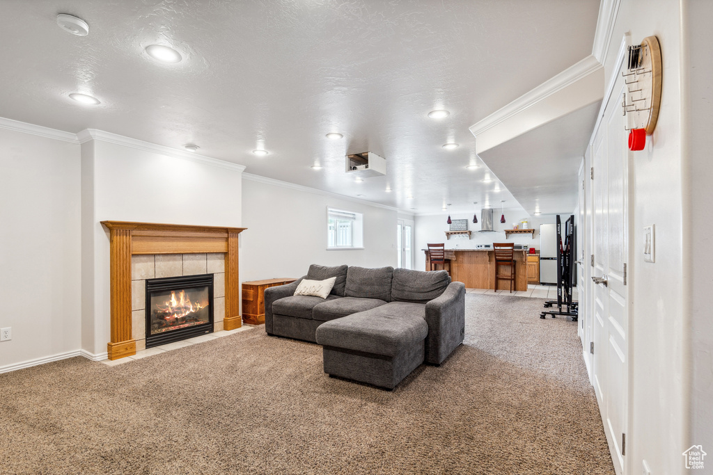 Living room featuring carpet flooring, crown molding, a fireplace, recessed lighting, and bar