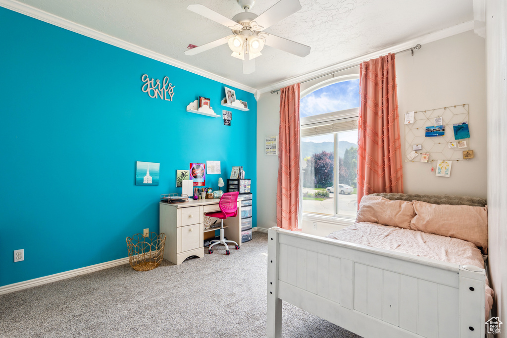 Carpeted bedroom featuring ornamental molding and a ceiling fan