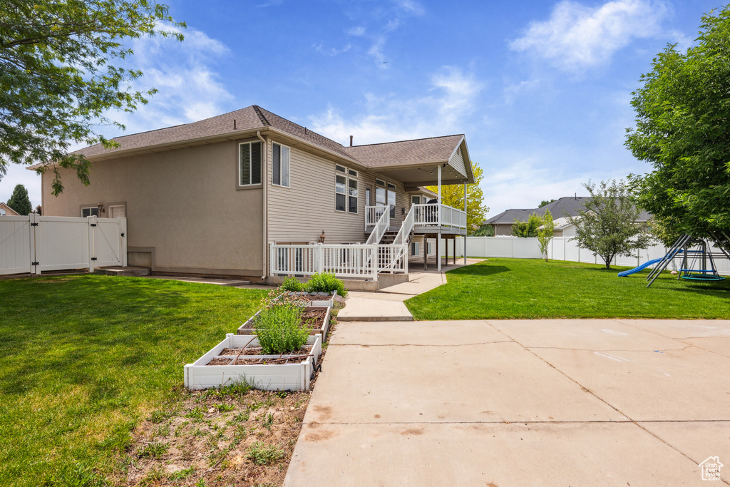 Rear view of property with a gate, a vegetable garden, stairs, a playground, and stucco siding