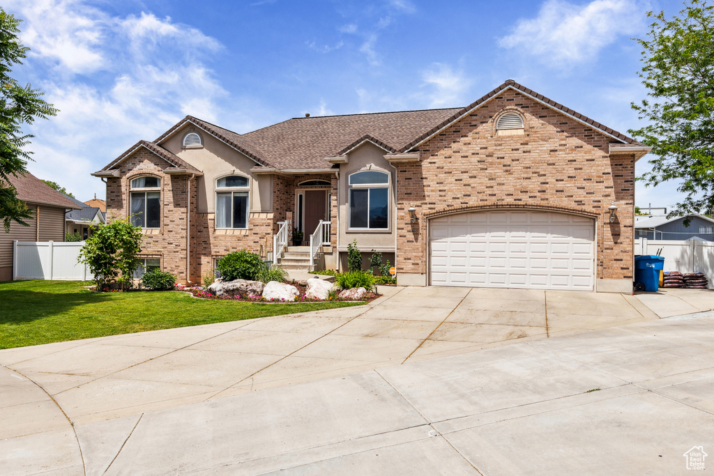 View of front of home with concrete driveway, a garage, and brick siding
