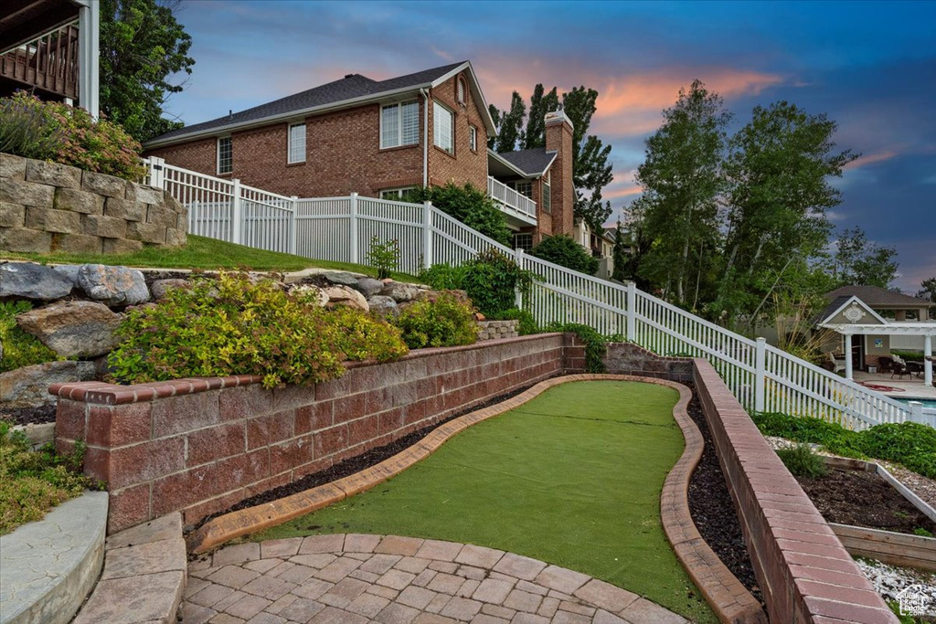 Yard at dusk featuring a putting area and a fenced backyard
