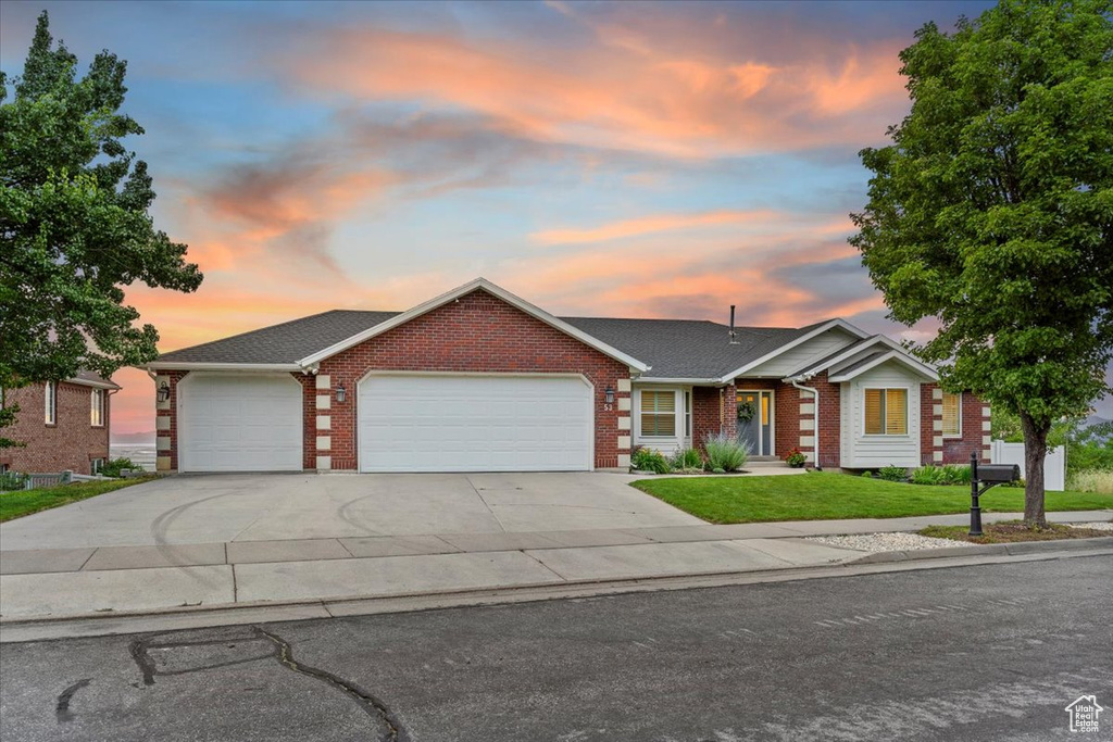 Single story home with brick siding, a garage, a yard, and concrete driveway