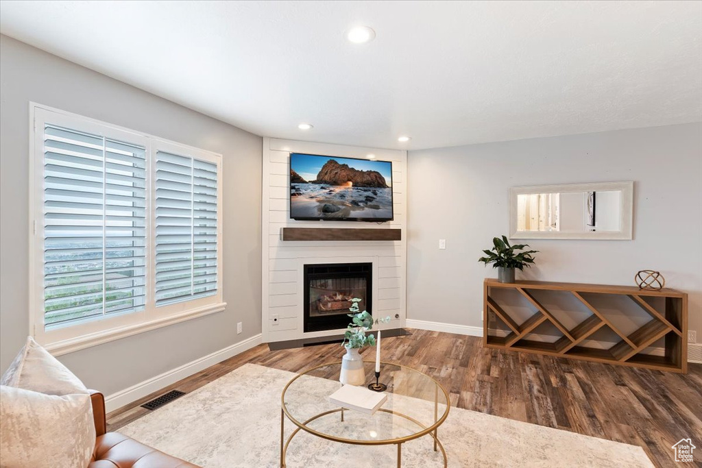 Living room with wood finished floors, healthy amount of natural light, recessed lighting, and a fireplace