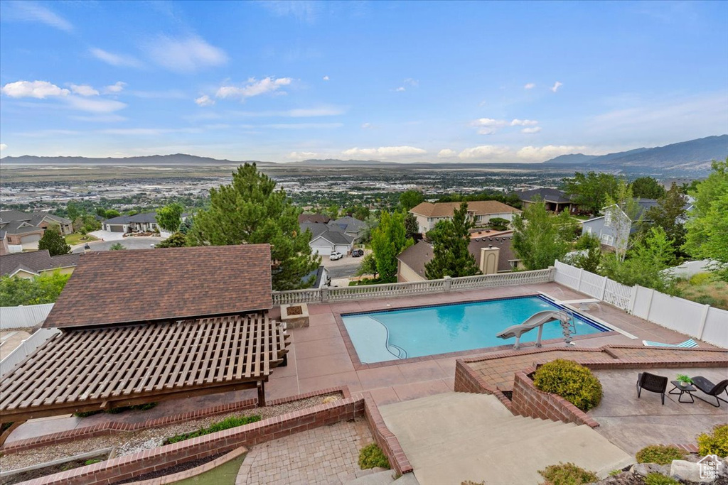 View of swimming pool with a fenced backyard, a mountain view, a patio, and a residential view