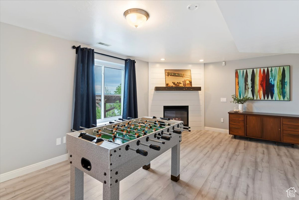 Recreation room featuring light wood-style floors, a fireplace, and recessed lighting