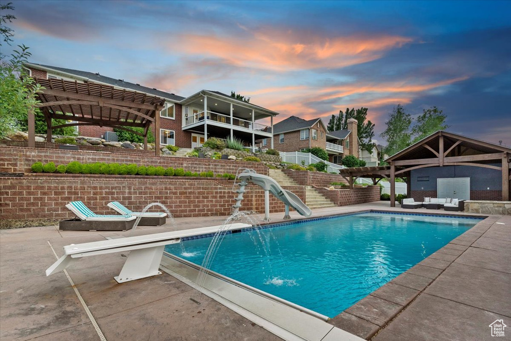 View of swimming pool with a water slide, a pergola, a patio area, and an outdoor hangout area