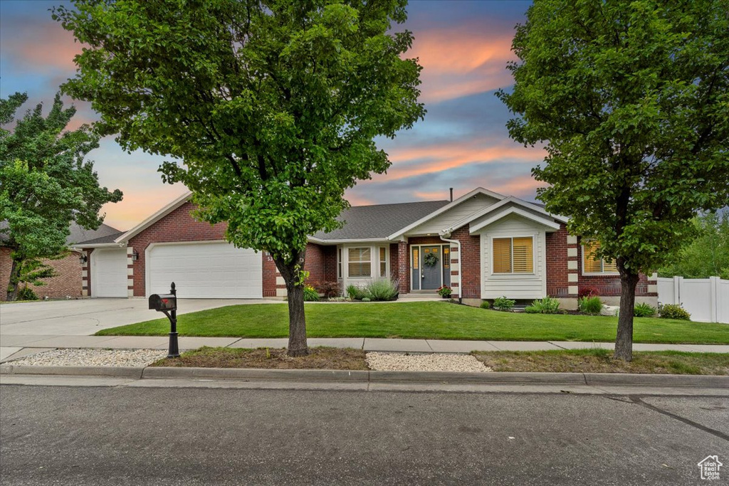 Ranch-style home featuring brick siding, an attached garage, and concrete driveway