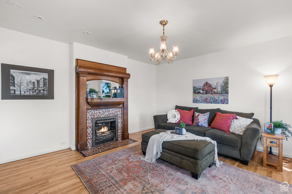 Living room with wood finished floors, a chandelier, and a tiled fireplace