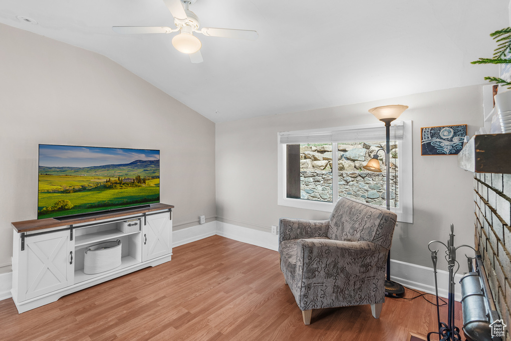 Living area featuring lofted ceiling, light wood-style flooring, and a ceiling fan