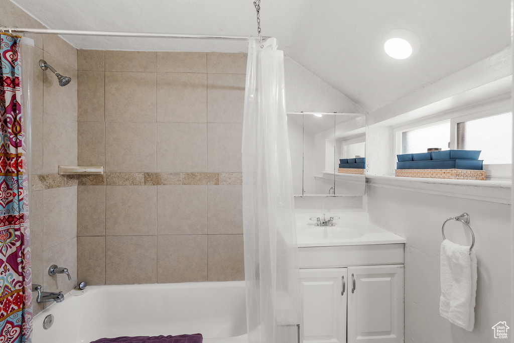 Bathroom with shower / tub combo, vanity, and vaulted ceiling