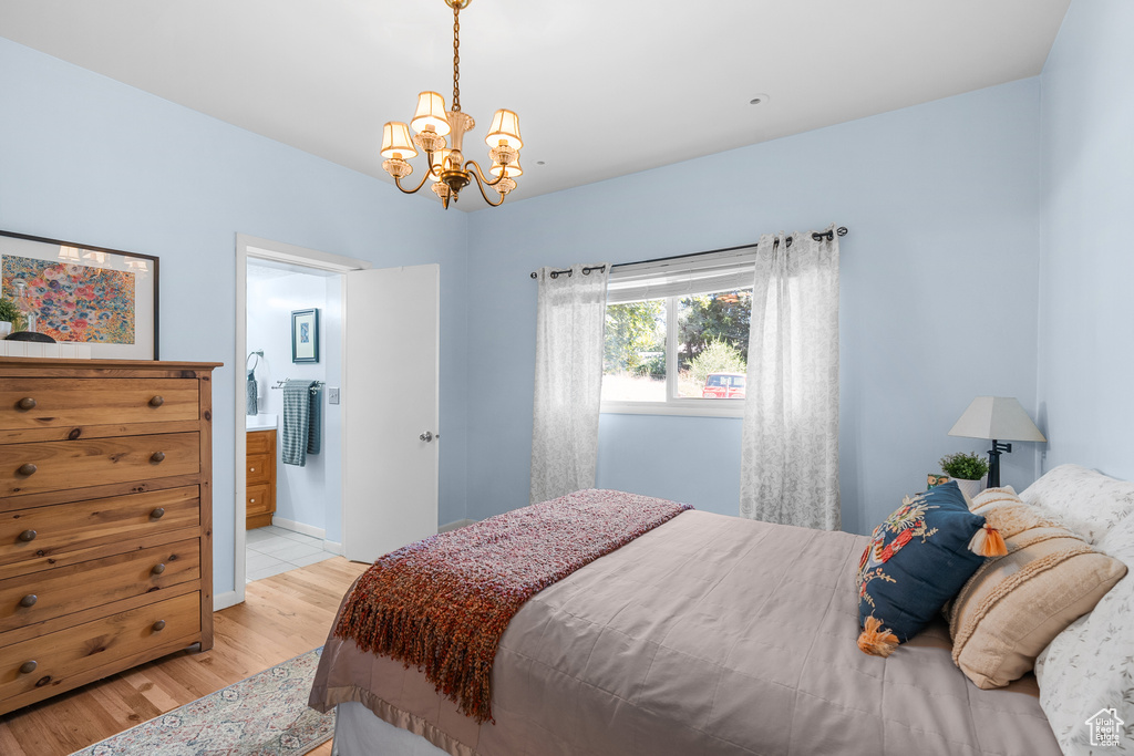 Bedroom featuring light wood-type flooring, a chandelier, and ensuite bathroom