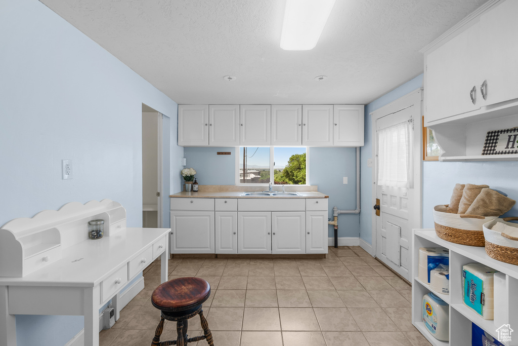 Kitchen with white cabinetry, light countertops, light tile patterned flooring, open shelves, and a textured ceiling