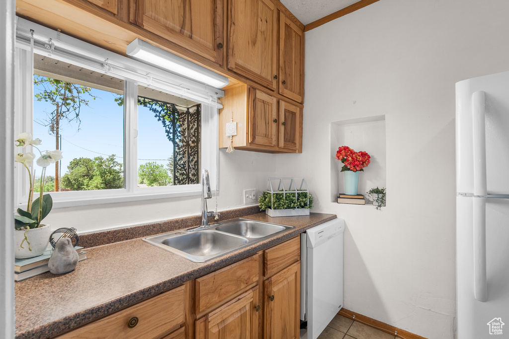 Kitchen with white appliances, plenty of natural light, dark countertops, and light tile patterned floors