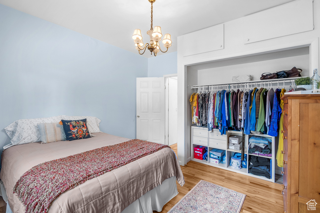 Bedroom featuring wood finished floors, a chandelier, and a closet