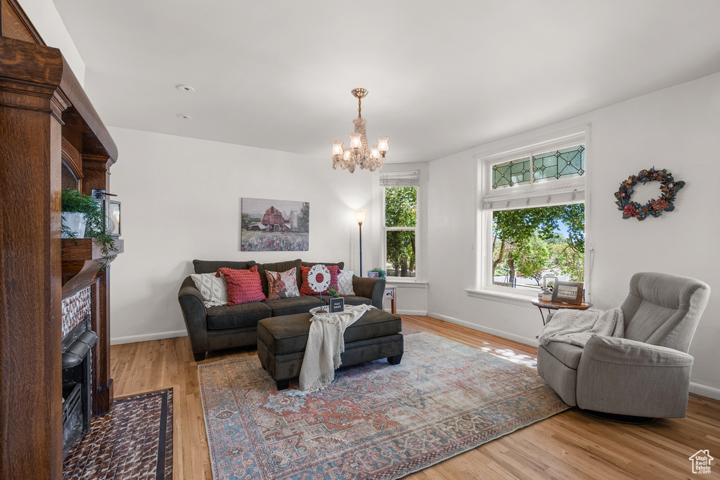 Living area featuring a chandelier, wood finished floors, and a fireplace with flush hearth